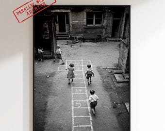 Fotografía vintage en blanco y negro de niños jugando a la rayuela, cuadro nostálgico de una escena callejera.