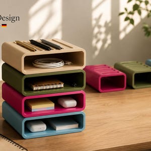 Op de afbeelding: Een stapel van vier rechthoekige opbergorganizers met open voorzijde in beige, olijfgroen, magenta en blauw. Elke unit heeft een bovenzijde met groeven. De tekst MizanDesign Made in Germany is zichtbaar in de linkerbovenhoek van de afbeelding.