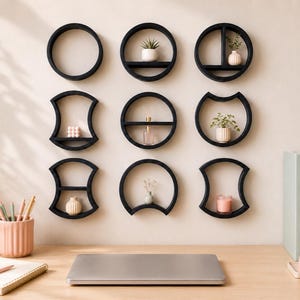 Puede incluir: Una colección de nueve estantes de pared negros con diversas formas geométricas, incluyendo círculos y marcos curvos, dispuestos en cuadrícula. Cada estante sostiene pequeños objetos decorativos como plantas, jarrones y velas.