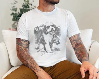 May include: A white short-sleeved t-shirt featuring a gray graphic print of a dog wearing sunglasses and holding a beer bottle labeled with XXX. The design is centered on the chest of the shirt, showcasing a detailed illustration of the canine.