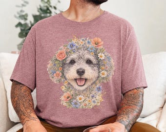 Puede incluir: Una camiseta de manga corta en color malva jaspeado con un gráfico central de la cara de un perro peludo rodeada por un arreglo colorido de varias flores, incluyendo rosas, margaritas y flores azules.