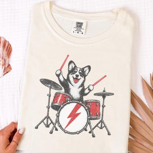 Maglietta per papà Corgi, idea regalo per batterista, maglietta rock con cane, maglietta per appassionati di musica, Corgi che suona la batteria, regalo divertente per amanti dei cani, maglietta con merchandising di una band immagine 3