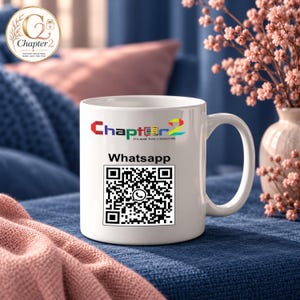 May include: A white ceramic mug featuring a colourful logo with the text Chapter 2 and the phrase IT'S MORE THAN A BOOKSTORE. Below the logo, the word Whatsapp is printed above a black and white QR code containing a small central icon.