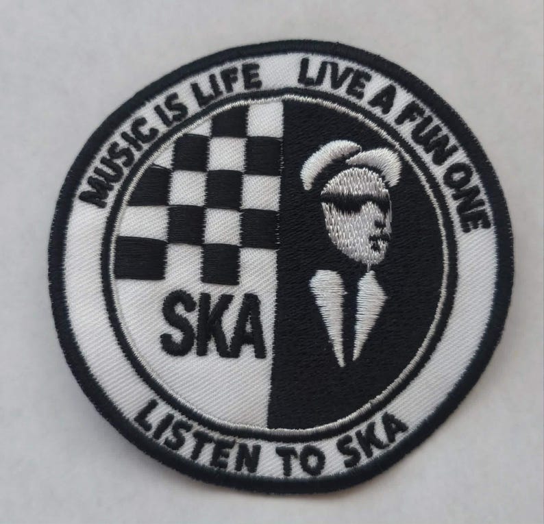 K&ouml;nnte beinhalten: Runder, gestickter Aufn&auml;her mit einem schwarz-wei&szlig;en Schachbrettmuster und einer Silhouette eines Mannes mit Sonnenbrille. Der Text lautet "MUSIC IS LIFE LIVE A FUN ONE" und "SKA LISTEN TO SKA".