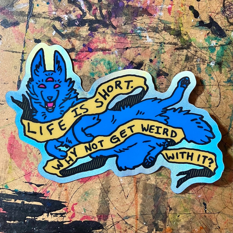May include: A blue and yellow holographic sticker with a cartoon wolf with three eyes. The wolf is holding a yellow banner that says "Life is short. Why not get weird with it?"