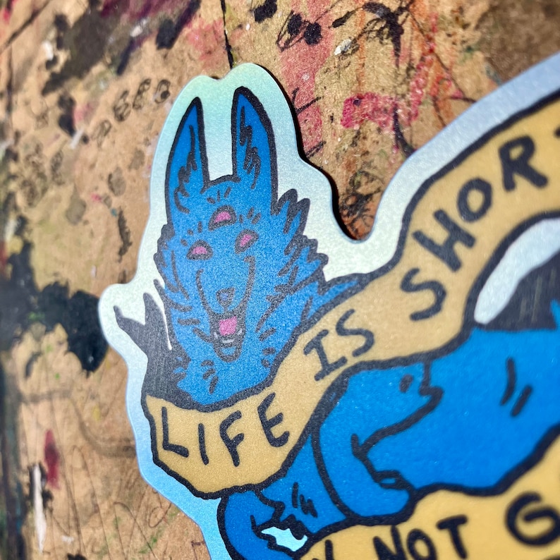 May include: A blue and yellow sticker with a cartoon wolf with three eyes and the text "Life is short don't not go"