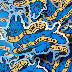 May include: A blue holographic sticker with a cartoon wolf-like creature with three eyes. The creature is holding a banner that says "Life is short. Why not get weird with it?"