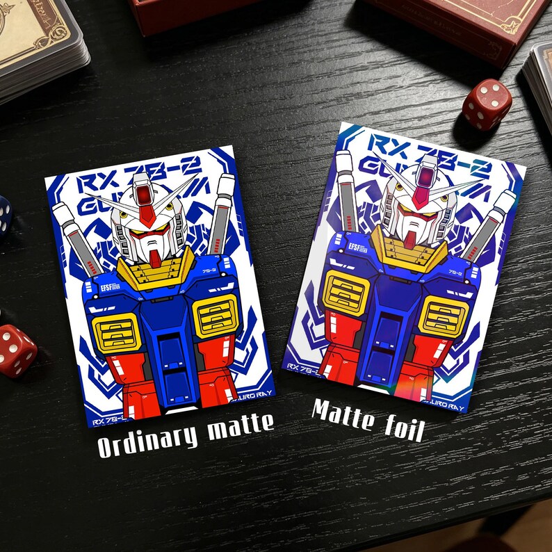 May include: Two trading card sleeves featuring a robot design in red, blue, white, and yellow. The text "RX 78-2" and "Ordinary matte" are visible on one sleeve, and "Matte foil" on the other. The cards are on a black surface.