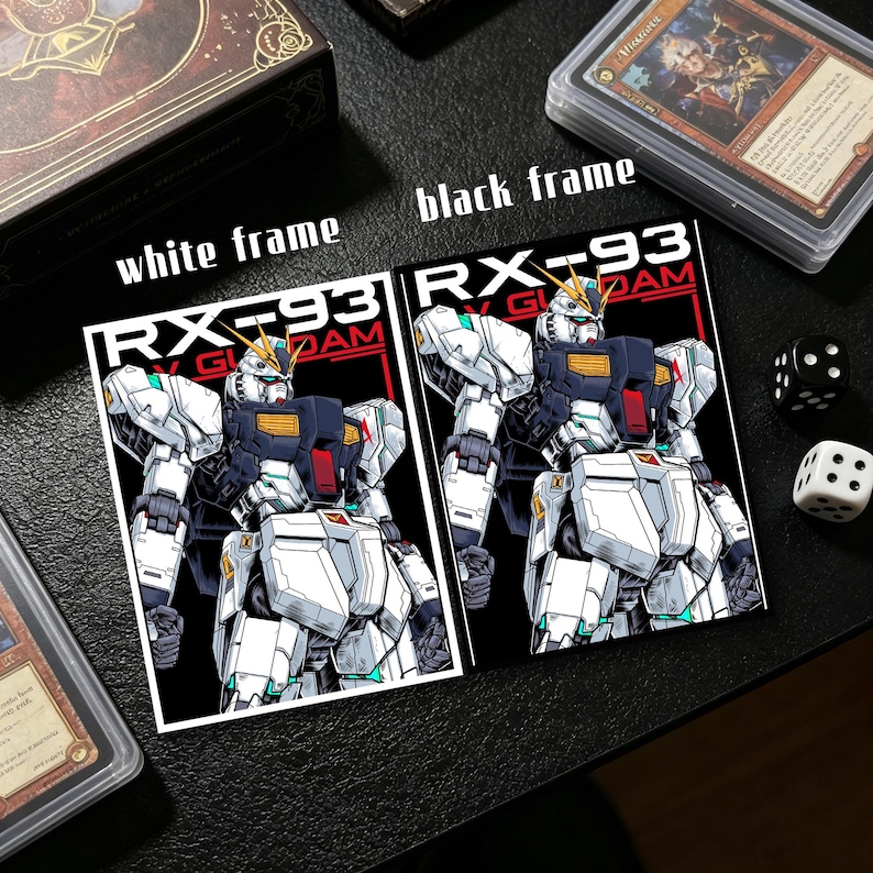 Puede incluir: Dos pegatinas con una ilustraci&oacute;n detallada de un robot RX-93 Gundam blanco, negro y rojo. Una pegatina tiene un marco blanco, la otra un marco negro. El texto "RX-93 GUNDAM" es visible. Dados y estuches de cartas en el fondo.
