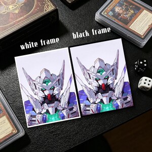 Op de afbeelding: Twee kaarthoezen, &eacute;&eacute;n met een witte lijst en &eacute;&eacute;n met een zwarte lijst, elk met een gedetailleerde illustratie van een robot met witte, blauwe en groene accenten. De tekst "white frame" en "black frame" staat boven de kaarten. Dobbelstenen en kaartenboxen zijn ook zichtbaar.