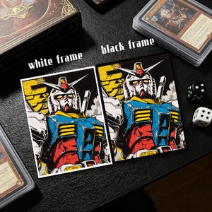 May include: Two trading card sleeves featuring a robot illustration, one with a white frame and the other with a black frame. The robot is primarily blue, red, yellow, and white. Dice and other card sleeves are also visible.