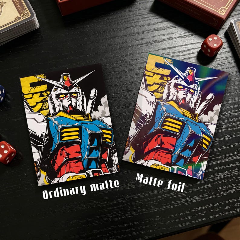 May include: Two trading cards featuring a colorful illustration of a robot. One card is labeled "Ordinary matte" and the other "Matte foil." The robot is primarily blue, red, yellow, and white, with a detailed design. The cards are on a black surface.