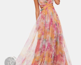 May include: A floor-length sleeveless gown featuring a vibrant watercolor-style floral print in shades of pink, orange, and yellow. The dress has a V-neckline, thin spaghetti straps, and a crisscross bodice design with a flowing, layered tulle skirt.