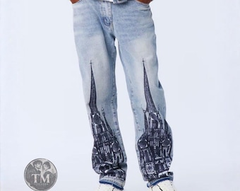 Può includere: Jeans in denim azzurro con una stampa grafica blu scuro di una cattedrale gotica su ogni gamba. I pantaloni presentano un classico design a cinque tasche con chiusura a bottoni e sono abbinati a una giacca in denim azzurro.