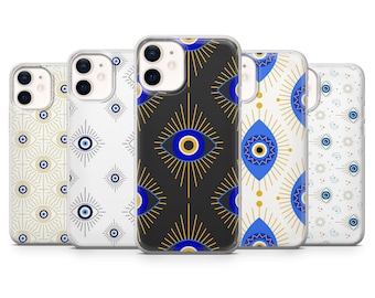 May include: Five clear smartphone cases arranged in a row, each featuring a distinct repeating pattern of blue, white, and gold evil eye symbols. The designs vary from fine gold line work to bold blue and gold graphic eye motifs on different backgrounds.