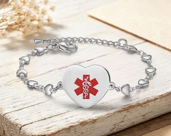May include: A silver-toned medical alert bracelet featuring a central heart-shaped charm with a red Star of Life symbol. The chain is composed of small, interconnected silver heart links and includes a lobster claw clasp for secure fastening.