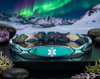 Puede incluir: Una pulsera de alerta médica con un acabado metálico iridiscente y multicolor, que presenta una placa ovalada central con el símbolo blanco de la Estrella de la Vida. La pulsera está formada por eslabones entrelazados en forma de X y un cierre.