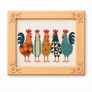 May include: A framed cross-stitch artwork featuring five colorful rooster designs. Each rooster has a unique pattern, including polka dots, stripes, and floral motifs. The frame is made of light-colored wood with floral corner accents.