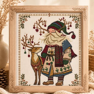 Peut inclure: Une broderie au point de croix encadrée représentant un personnage barbu portant un chapeau vert et bleu avec des bois décorés de petits ornements, debout à côté d'un renne aux bois décorés, le tout dans une bordure décorative.