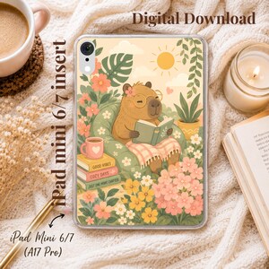 Puede incluir: Una lámina para funda de iPad mini 6/7 con un capibara con gafas leyendo un libro en un sillón verde. La ilustración incluye flores, un sol y una pila de libros con los textos Good Vibes, Cozy Days y Just One More Chapter.