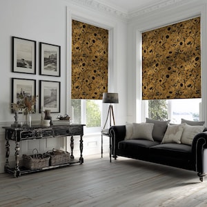 Può includere: Vista interna di un soggiorno con due finestre con tende a rullo decorate. Le tende presentano un motivo floreale oro e nero. Un divano nero con cuscini è posizionato di fronte alle finestre. Una consolle nera anticata è in primo piano.