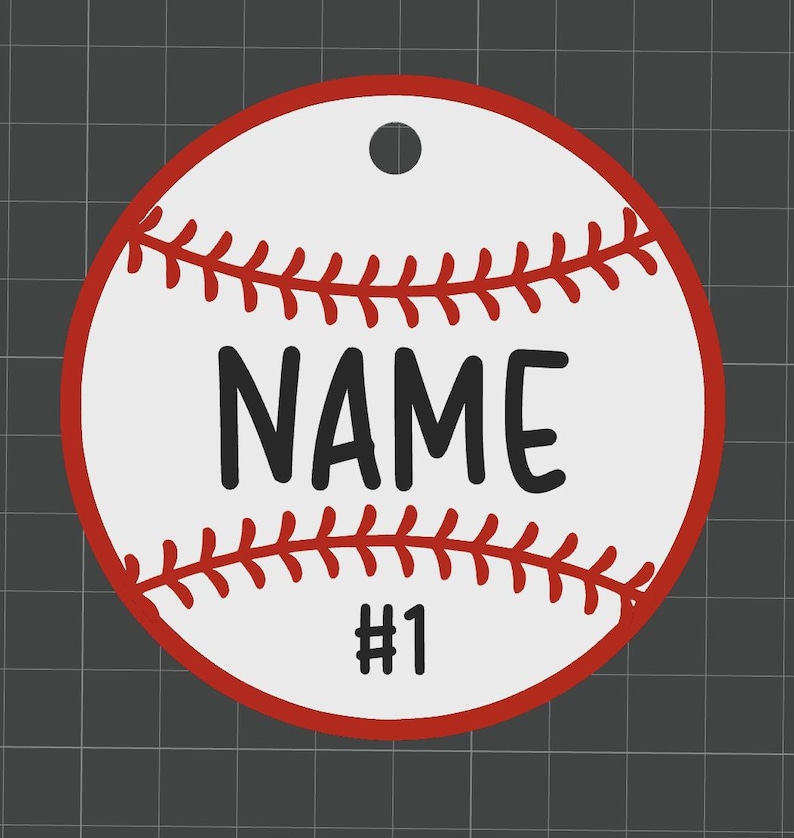 Puede incluir: Adorno con tem&aacute;tica de b&eacute;isbol con fondo blanco, costuras rojas y borde rojo. La palabra "NAME" est&aacute; impresa en letras negras en negrita, con el n&uacute;mero "1" debajo. Hay un agujero en la parte superior para colgar.