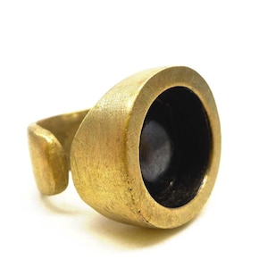 Pode incluir: Um anel dourado com uma configuração de engaste redonda. O engaste está vazio e pronto para ser preenchido com uma pedra ou outro enfeite.