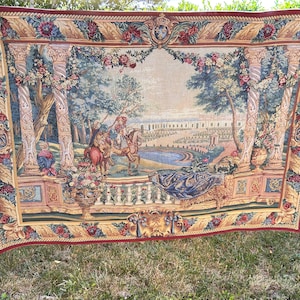 May include: A rectangular woven tapestry featuring a scene of figures on horseback within a garden setting framed by ornate columns and floral garlands. The border is deep red with gold accents, and the central image depicts a landscape.