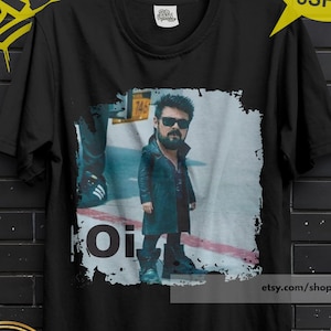 May include: Black t-shirt featuring a graphic of a man in sunglasses and a long coat. The word "Oi" is printed on the shirt. The shirt has a "Premium Quality" seal and a "Buy 3, Free Shipping" promotion.