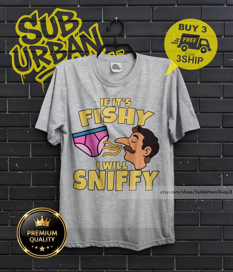 May include: A heather gray short-sleeve t-shirt featuring a graphic print of a pair of pink underwear and a cartoon face with a mustache. The text reads IF IT'S FISHY I WILL SNIFFY in yellow letters. The shirt has a crew neckline and a standard fit.