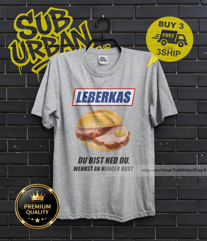 May include: A gray t-shirt featuring a Leberkas sandwich graphic with the text "LEBERKAS" above and "DU BIST NED DU, WENNST AN HUNGER HOST" below. The shirt also has a "Premium Quality" badge.
