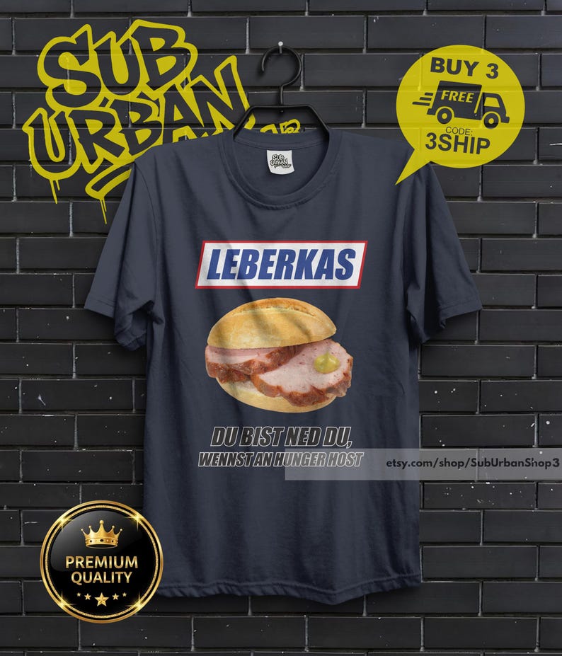 May include: Navy blue t-shirt featuring a Leberkas sandwich illustration. The word "LEBERKAS" is printed above the sandwich, with the phrase "DU BIST NED DU, WENNST AN HUNGER HOST" below. The shirt also has a "BUY 3 FREE" promotion.