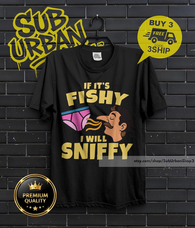 May include: A black short-sleeved t-shirt featuring a graphic print of pink underwear and a person sniffing them. The text reads IF IT'S FISHY I WILL SNIFFY in yellow capital letters. The shirt has a crew neckline and is displayed on a black hanger.