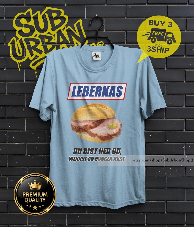 May include: Light blue t-shirt featuring a Leberkas sandwich graphic with the text "LEBERKAS" above and "DU BIST NED DU, WENNST AN HUNGER HOST" below. The shirt also has a "BUY 3 FREE" promotion graphic.