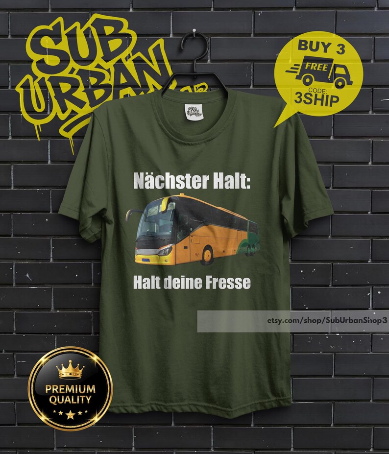 May include: Olive green t-shirt with a bus graphic and German text. The text reads "N&auml;chster Halt: Halt deine Fresse." A yellow sticker says "Buy 3 Free" with a code. The shirt hangs on a black hanger.