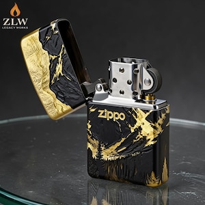 Może przedstawiać: Zapalniczka Zippo z czarno-złotym wzorem g&oacute;rskim. Zapalniczka jest otwarta, ukazując wnętrze. Logo Zippo jest widoczne z przodu. Logo ZLW Legacy Works znajduje się w lewym g&oacute;rnym rogu.