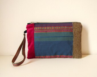 May include: A colorful striped clutch purse with a pink velvet panel, a brown fabric flap, and a zipper closure. The purse has a long strap.