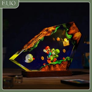 May include: A resin art piece depicting Mario and Yoshi from Super Mario Bros. within a geometric form, set on a wooden base. The scene includes coins, stars, and a question mark block. The piece has the text "ELIO RESIN ART".