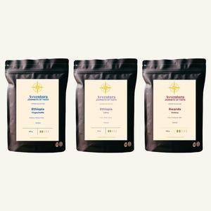 以下が含まれることがあります： 黄色いコンパスのロゴと「Avventura Journeys of Taste」の文字が記されたクリーム色のラベルが付いた、3つの黒いコーヒーバッグ。ラベルには「Ethiopia Yirgacheffe」、「Ethiopia Limu」、「Rwanda Inzovu」と記載されており、それぞれ250gと表示されています。