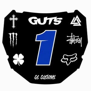 Könnte beinhalten: Schwarzes Motocross-Nummernschild mit einer blauen Nummer 1. Das Schild zeigt weiße Logos, darunter "GUTS", ein Kreuz, ein vierblättriges Kleeblatt und den Text "GS CUSTOMS".