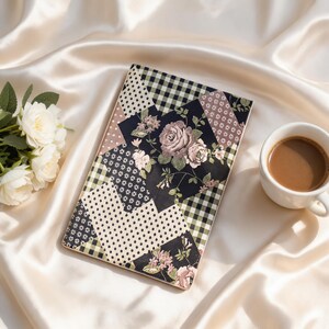 Puede incluir: Un cuaderno rectangular con un diseño de cubierta de patchwork que alterna secciones de cuadros vichy en blanco y negro, lunares, pequeños estampados florales y un panel central con una ilustración detallada de rosas rosadas sobre fondo negro.