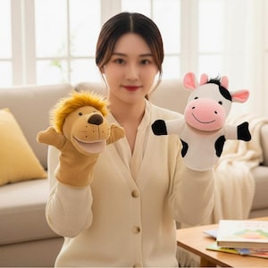 May include: Two plush hand puppets: a lion with a tan body and a yellow mane, and a cow with a white body, black spots, and pink ears. The puppets are designed for children's play and storytelling.