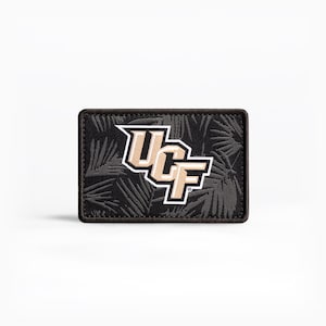 May include: A rectangular patch featuring the UCF logo in gold and white, set against a black background with a subtle palm leaf pattern. The patch has a black border.