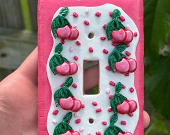 Lichtschalterabdeckung mit Kirschglasur-Toaster-Motiv | Handgefertigte Wandplatte aus Polymerclay | Hübsche Küchendekoration | Rosa Kirschstreusel-Dekoration