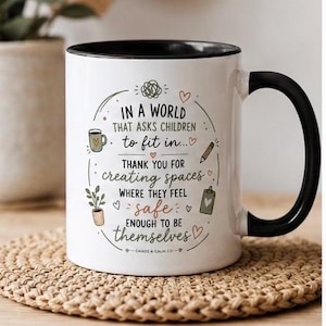 May include: A white ceramic mug with a black interior and handle, featuring the printed text: In a world that asks children to fit in, thank you for creating spaces where they feel safe enough to be themselves, surrounded by small illustrations.