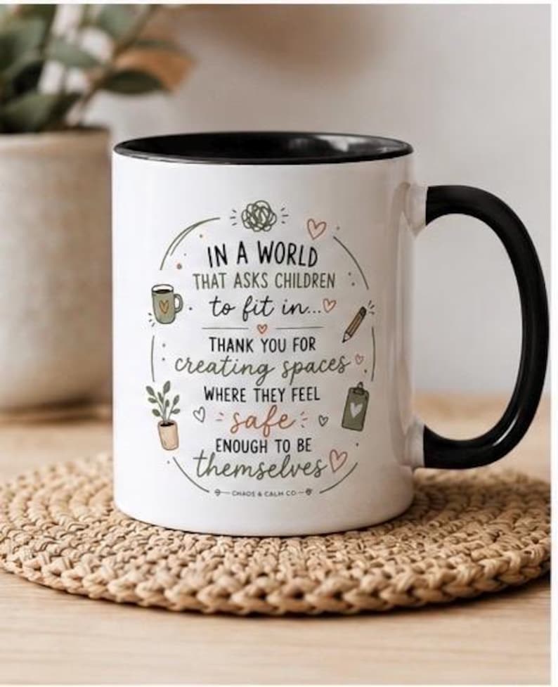 May include: A white ceramic mug with a black interior and handle, featuring the printed text: In a world that asks children to fit in, thank you for creating spaces where they feel safe enough to be themselves, surrounded by small illustrations.