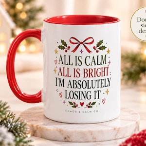 May include: A white ceramic mug with a red interior and handle, featuring the text "ALL IS CALM ALL IS BRIGHT I'M ABSOLUTELY LOSING IT" in black and red, surrounded by holly, a red bow, and small hearts and stars. The text "CHAOS & CALM CO." is printed below.