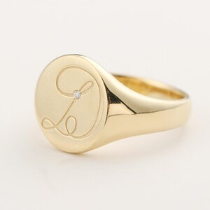 Anel de sinete em ouro com detalhes em diamante e monograma.