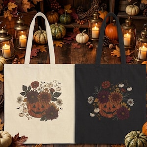 May include: Two rectangular tote bags, one in cream and one in black, each featuring a central graphic of a carved jack-o'-lantern surrounded by dark red and orange autumn flowers, green leaves, small white pumpkins, and tiny flying bats.