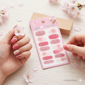 Könnte beinhalten: Eine Packung rosa Gel-Nagelaufkleber mit verschiedenen Designs, darunter Glitzer und Blumenakzente. Eine Hand mit lackierten Nägeln zeigt ein passendes Design. Der Text "Gel Nail Seal" ist auf der Verpackung zu sehen.